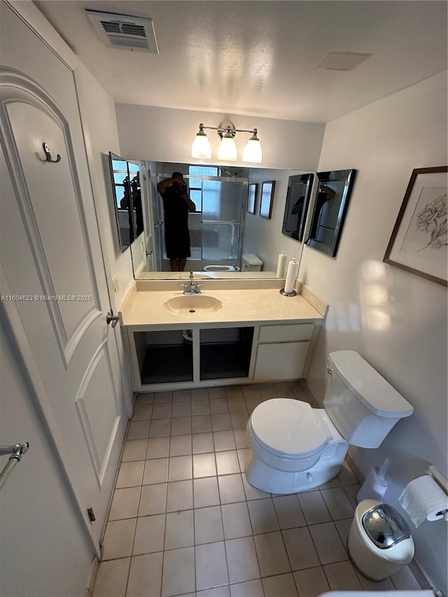 bathroom with toilet, vanity, and tile patterned flooring