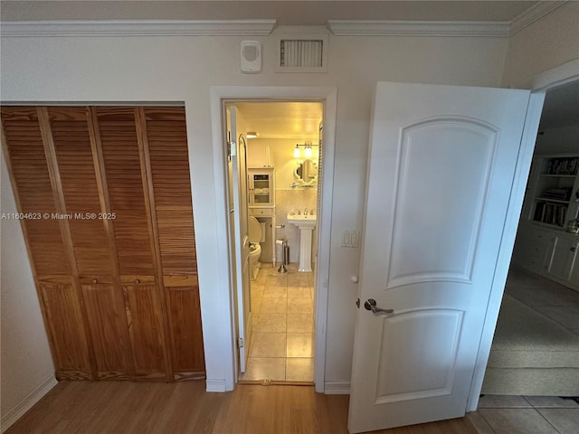 hall with light tile patterned floors and crown molding