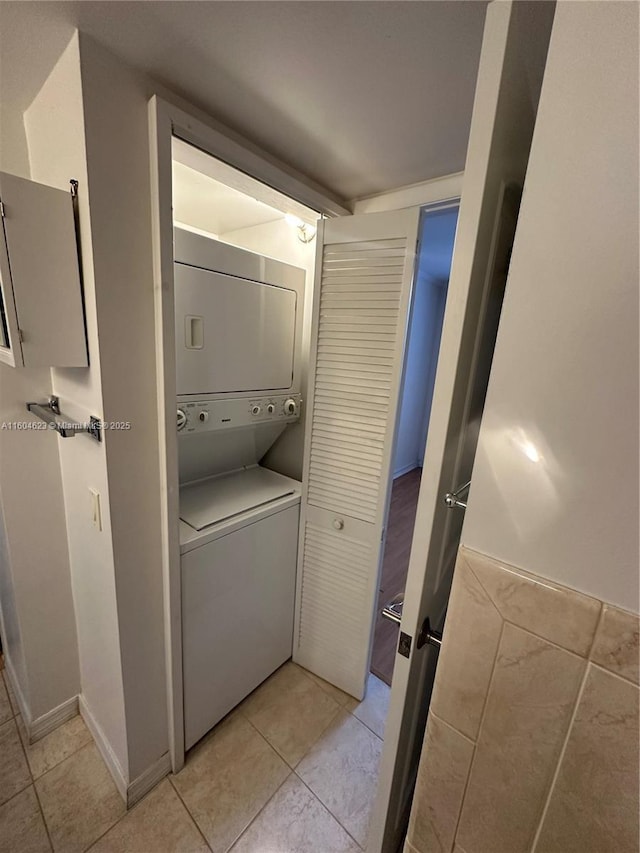 washroom with light tile patterned flooring and stacked washer and clothes dryer