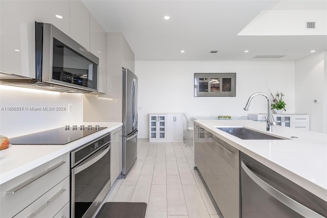 kitchen featuring sink, light tile flooring, gray cabinetry, and stainless steel appliances