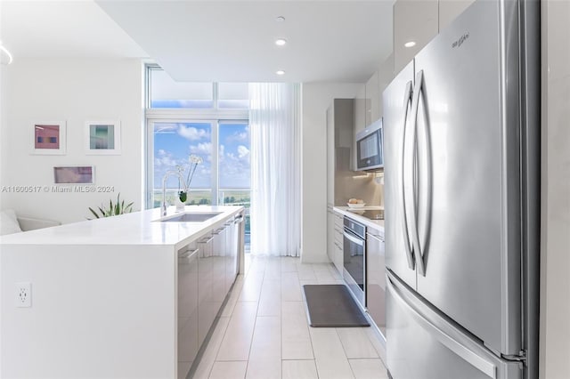 kitchen featuring appliances with stainless steel finishes, sink, an island with sink, and light tile floors