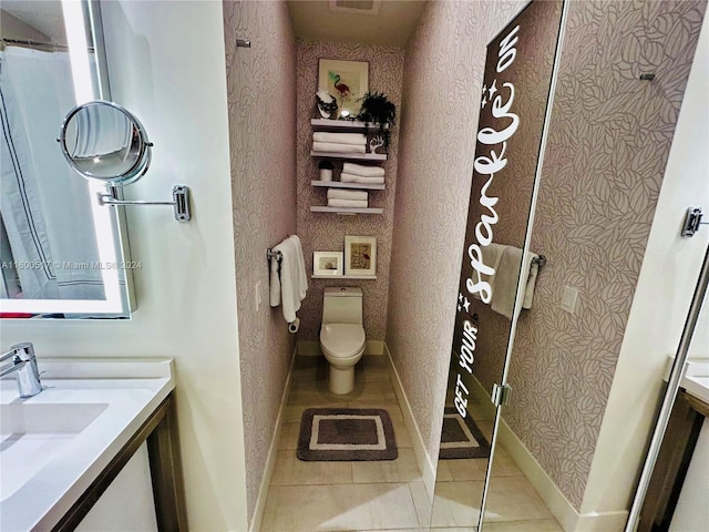 bathroom with tile floors, vanity, and toilet