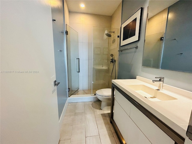 bathroom with tile floors, a shower with door, toilet, and large vanity