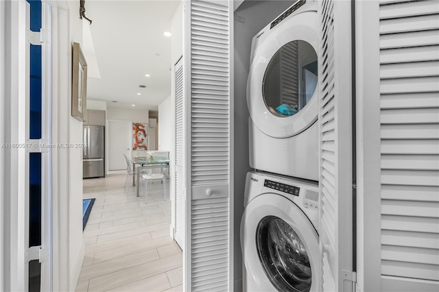 laundry area with stacked washer / dryer and light wood-type flooring