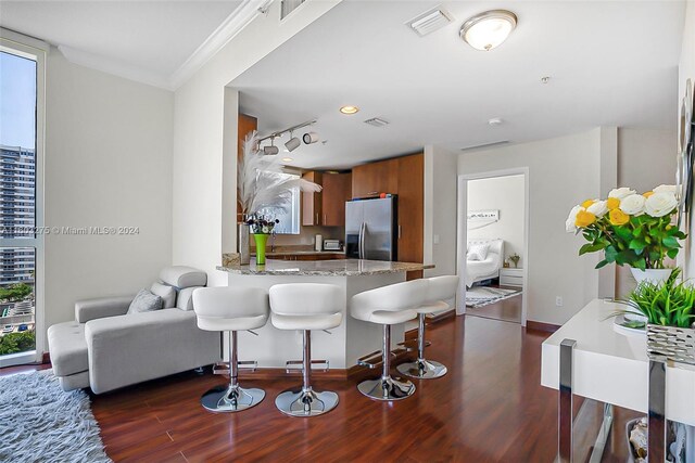 kitchen with light stone counters, kitchen peninsula, rail lighting, a breakfast bar area, and stainless steel fridge