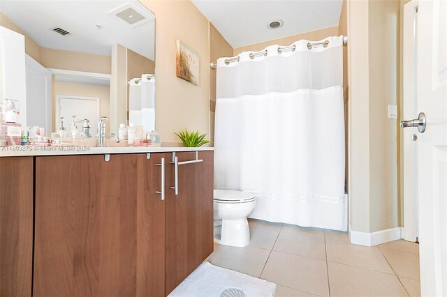 bathroom with tile flooring, toilet, and oversized vanity