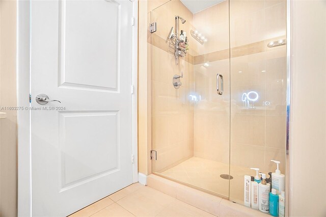 bathroom with tile flooring and a shower with shower door