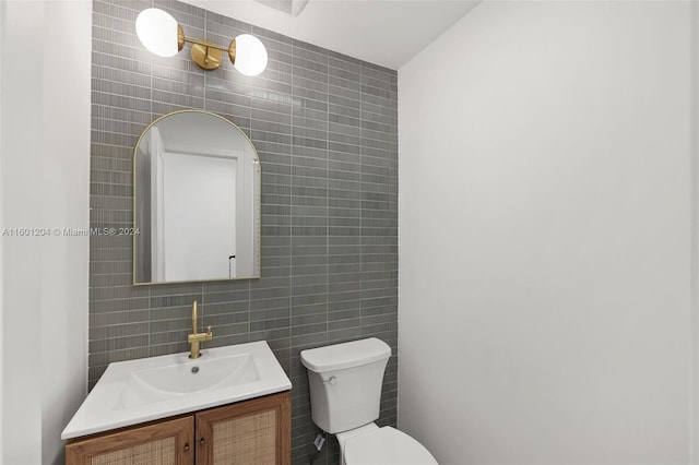 bathroom featuring vanity, toilet, and tile walls