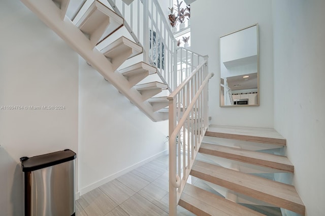 staircase with an inviting chandelier and light tile patterned floors