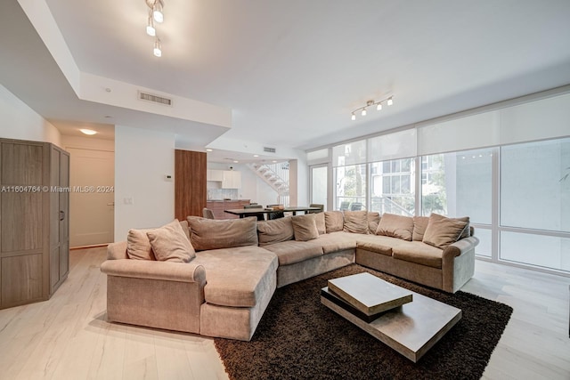 living room with rail lighting and light hardwood / wood-style floors