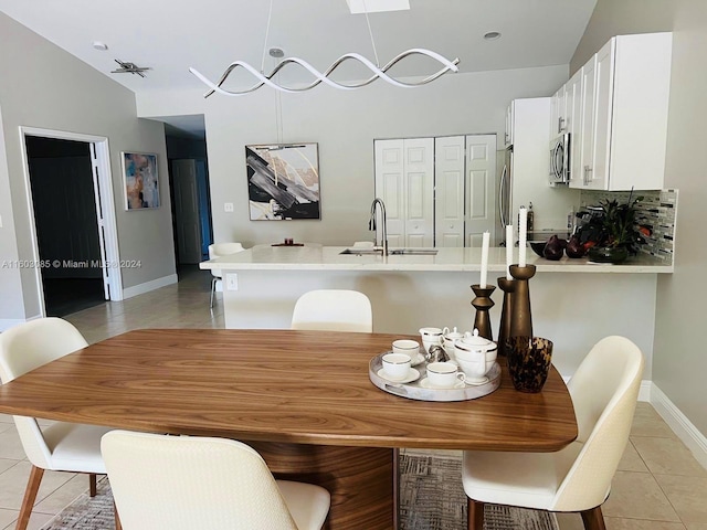 dining room with sink, light tile flooring, vaulted ceiling, and an inviting chandelier