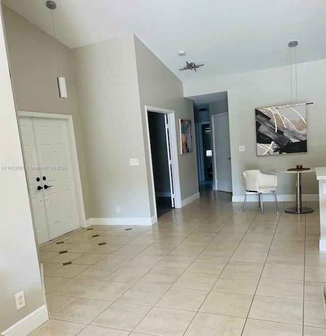 interior space featuring high vaulted ceiling, baseboards, and light tile patterned floors