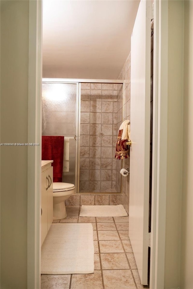 bathroom featuring tile patterned floors, vanity, toilet, and an enclosed shower