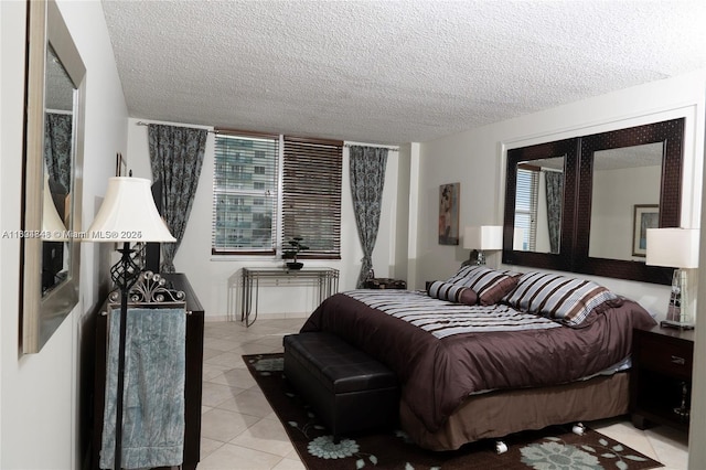 bedroom featuring french doors, light tile patterned floors, and a textured ceiling