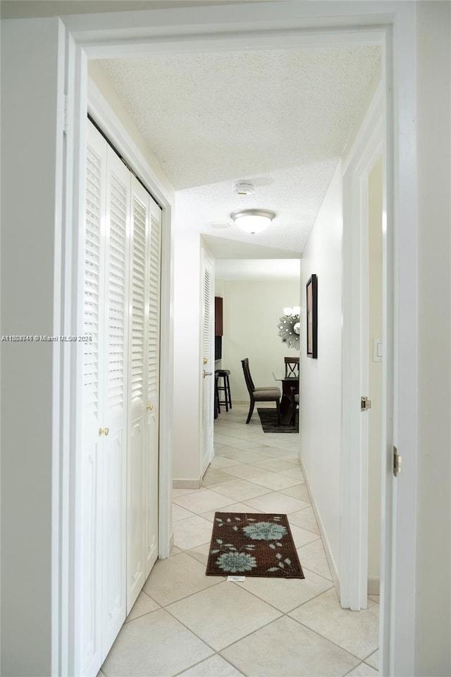 corridor with light tile patterned flooring and a textured ceiling