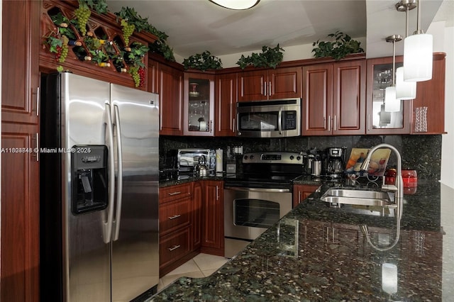 kitchen with backsplash, hanging light fixtures, sink, light tile patterned floors, and appliances with stainless steel finishes