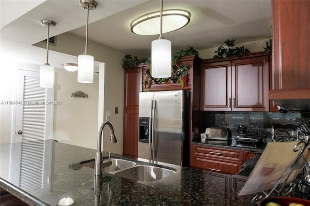 kitchen with sink, dark stone countertops, stainless steel fridge, decorative light fixtures, and decorative backsplash