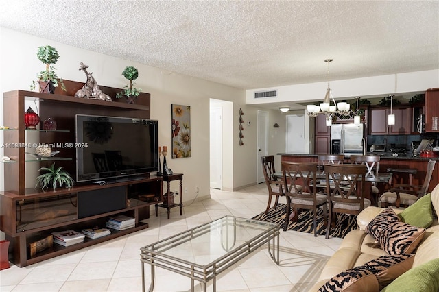 living room featuring light tile patterned floors, a textured ceiling, an inviting chandelier, and sink