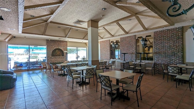 tiled dining room with beamed ceiling, brick wall, and a textured ceiling