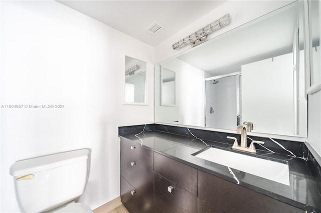 bathroom with vanity, toilet, and a shower with shower door