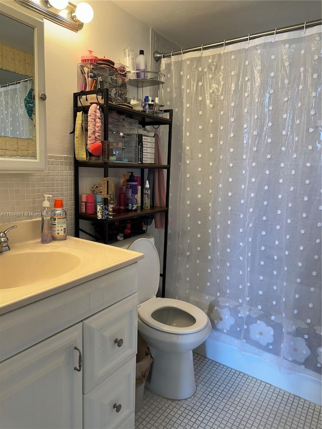 bathroom featuring tile patterned flooring, toilet, vanity, and backsplash