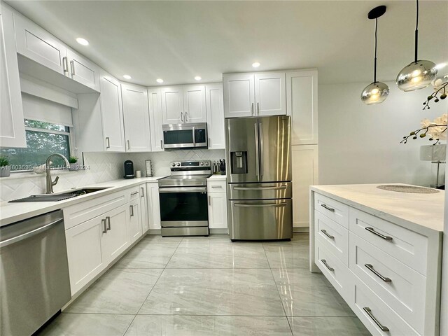 kitchen featuring stainless steel appliances, decorative light fixtures, backsplash, light tile floors, and white cabinetry