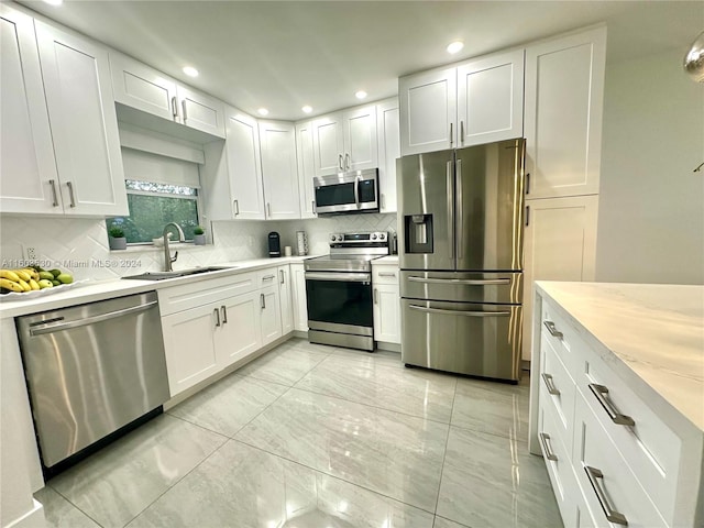 kitchen featuring light tile flooring, white cabinets, tasteful backsplash, and appliances with stainless steel finishes