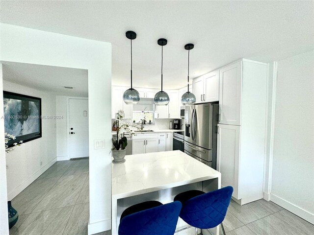 kitchen featuring kitchen peninsula, pendant lighting, white cabinets, sink, and appliances with stainless steel finishes