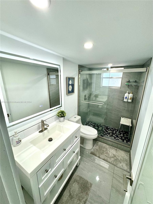 bathroom with an enclosed shower, tile flooring, vanity, and toilet