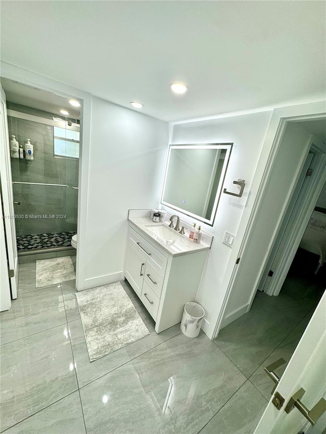 bathroom with tiled shower, tile flooring, toilet, and vanity with extensive cabinet space