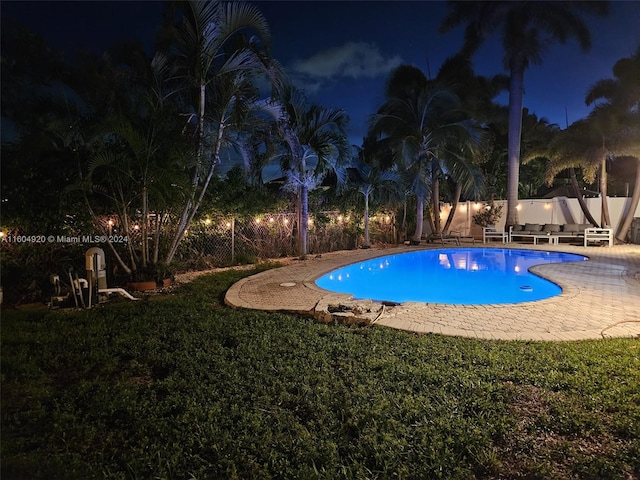 pool at night featuring a patio