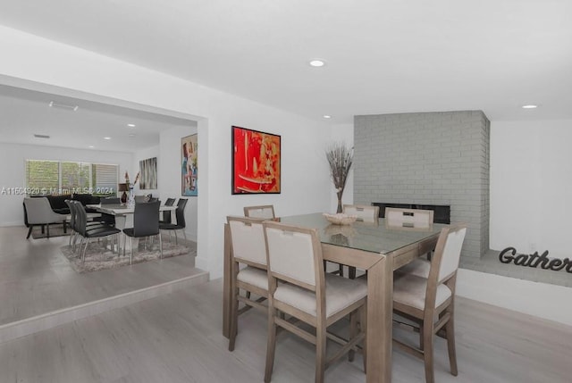 dining room featuring light wood-type flooring and brick wall