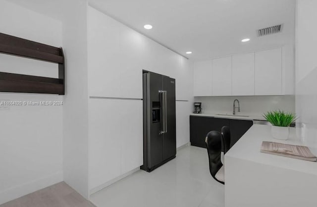 kitchen featuring sink, high end fridge, backsplash, and white cabinets