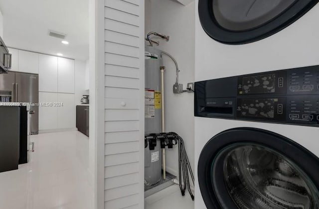 laundry area with light tile patterned floors, water heater, and stacked washer and clothes dryer