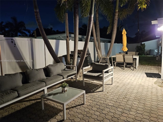 patio at night featuring outdoor lounge area and central air condition unit