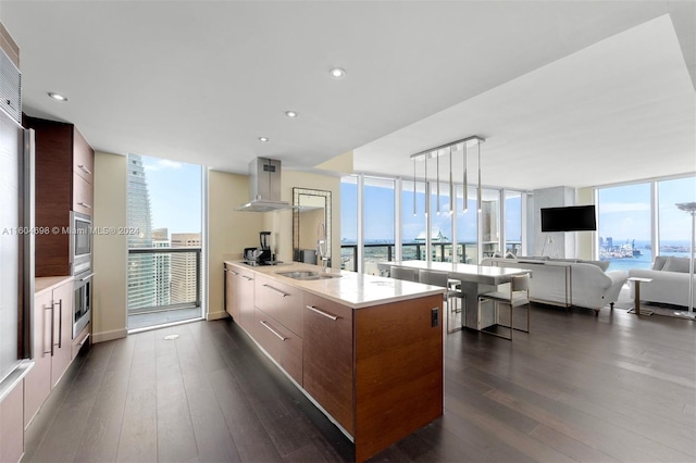 kitchen with floor to ceiling windows, dark wood-type flooring, wall chimney range hood, pendant lighting, and plenty of natural light