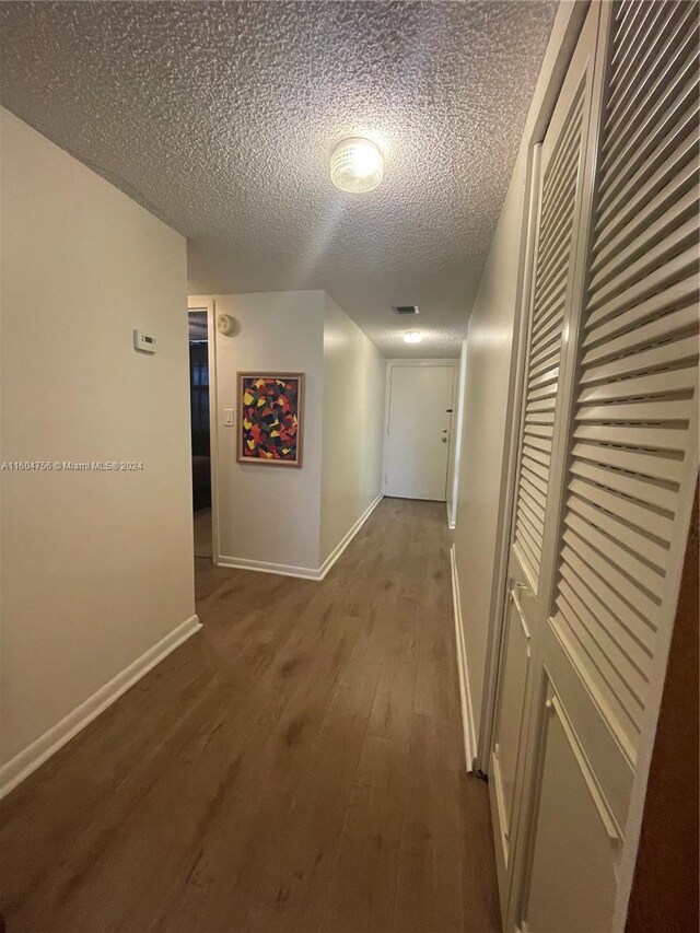 corridor featuring a textured ceiling and dark wood-type flooring