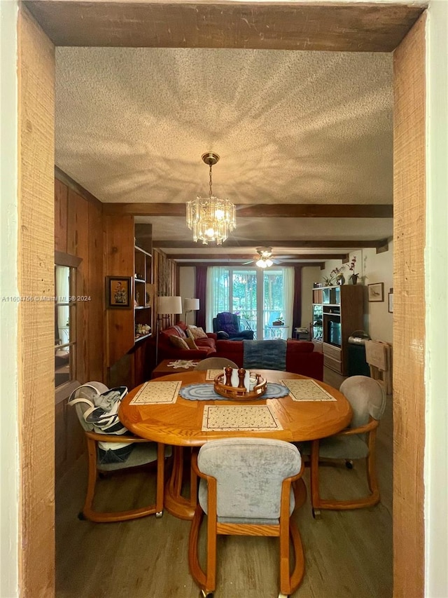 dining room with a textured ceiling, wooden walls, ceiling fan with notable chandelier, and hardwood / wood-style floors