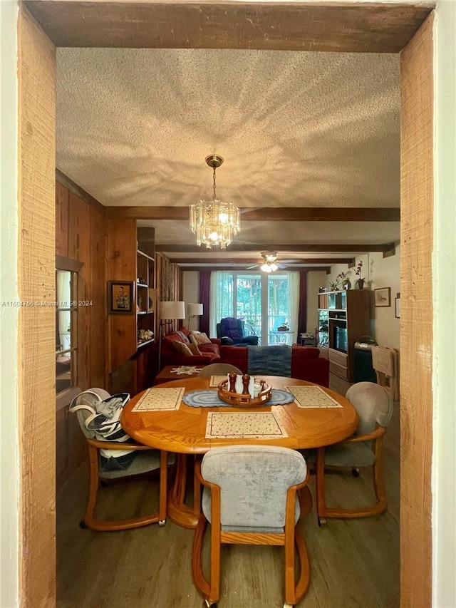 dining space with hardwood / wood-style flooring, beam ceiling, a chandelier, and wood walls