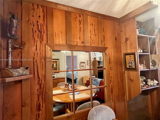 dining space with wooden walls and a textured ceiling