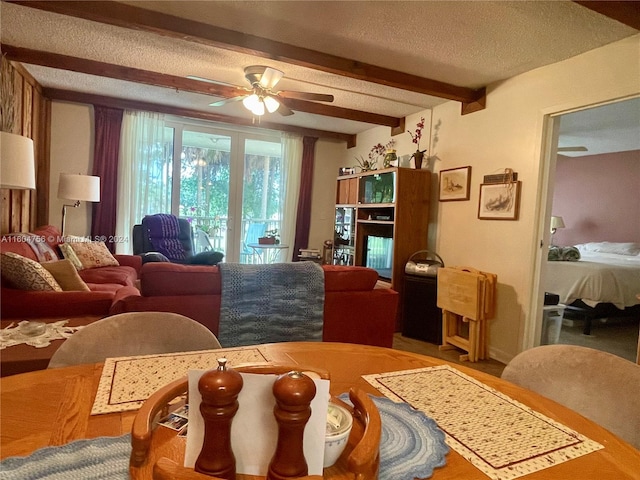 living room featuring ceiling fan, beam ceiling, and a textured ceiling