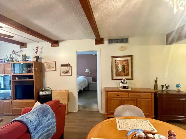 living room with beamed ceiling, a textured ceiling, and hardwood / wood-style floors