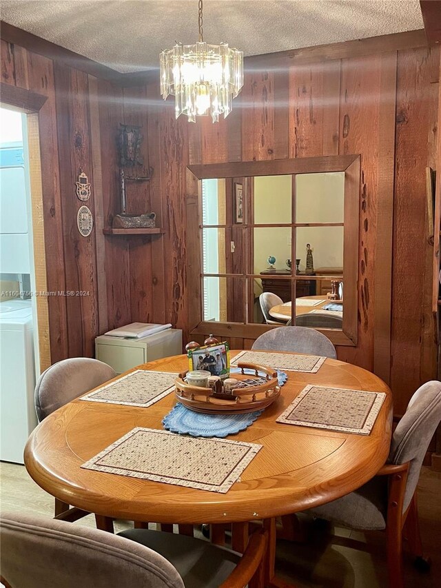 dining area with wooden walls, a textured ceiling, washer / clothes dryer, and a chandelier