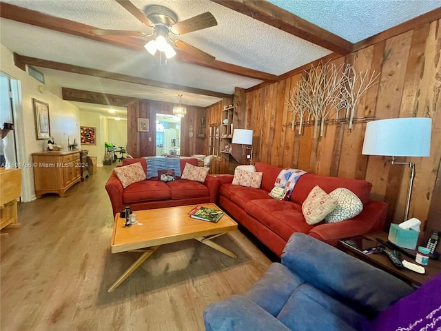 living room featuring a textured ceiling, wooden walls, beam ceiling, wood-type flooring, and ceiling fan