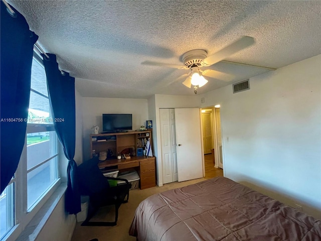 carpeted bedroom with a textured ceiling, a closet, and ceiling fan