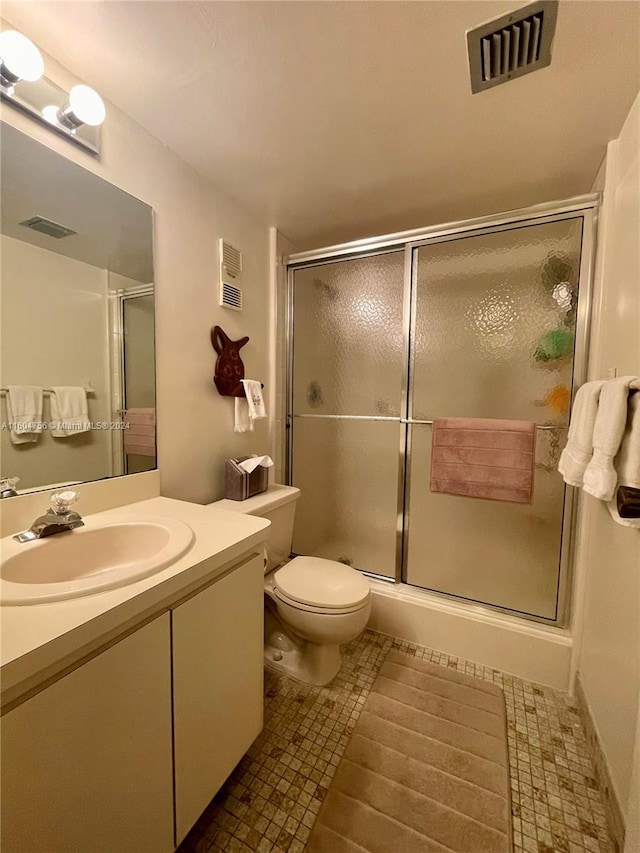 bathroom featuring tile floors, a shower with shower door, vanity, and toilet