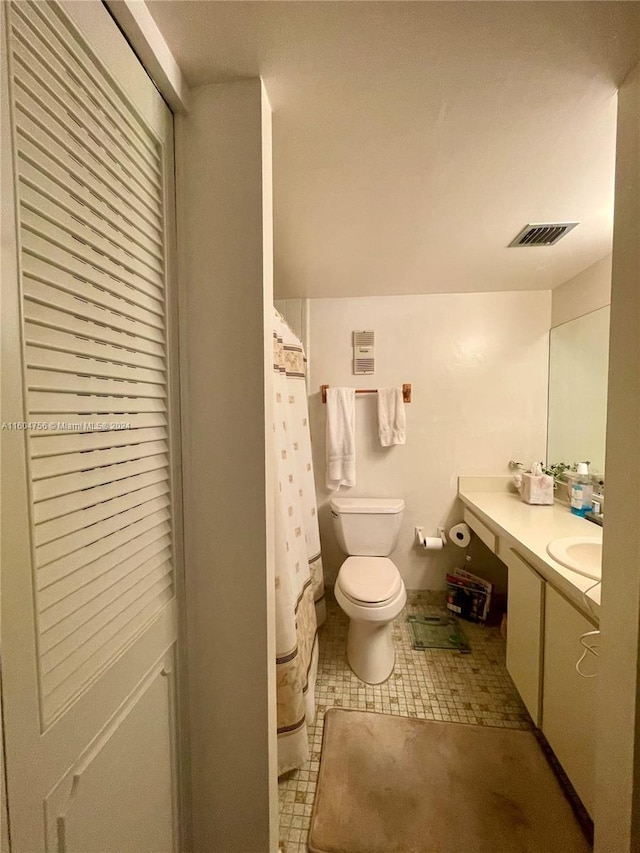 bathroom featuring tile flooring, vanity, and toilet