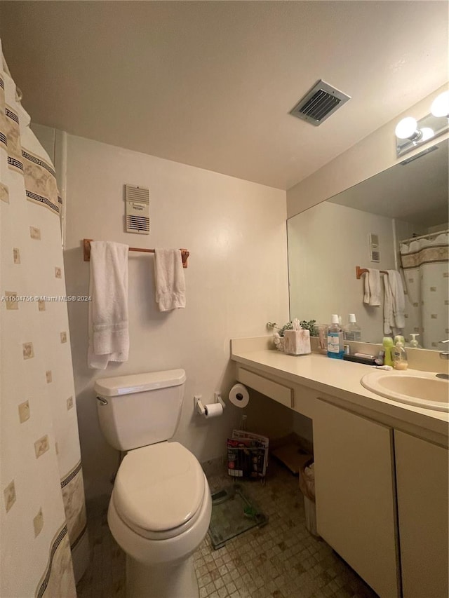 bathroom featuring tile flooring, vanity, and toilet