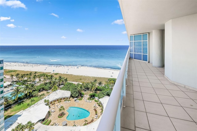 balcony featuring a view of the beach and a water view