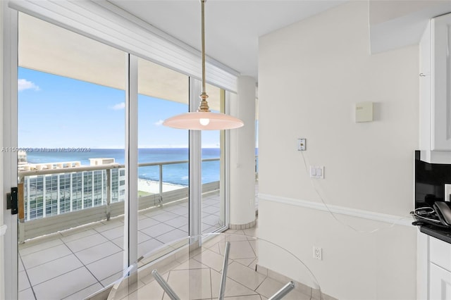 unfurnished dining area with a water view, light tile patterned flooring, and a beach view